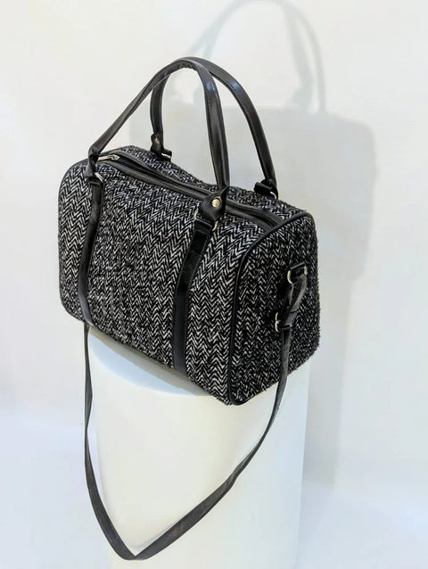 Black and white patterned handbag with a strap on a white background